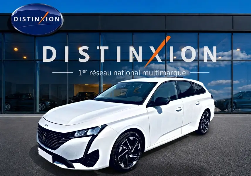 Peugeot 308 SW blanche vue en 3/4 avant droit, avec jantes alliage noires et calandre noire distinctive.