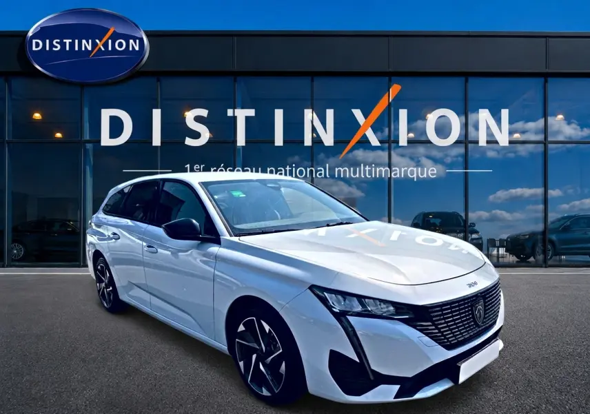 Peugeot 308 SW blanche vue en 3/4 avant droit, avec jantes alliage et calandre noire distinctive.