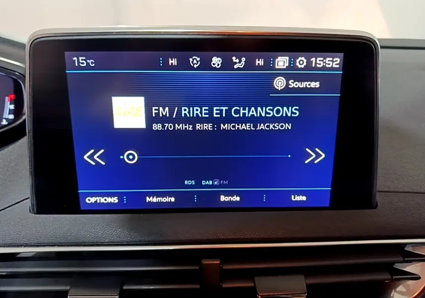 Écran tactile central du tableau de bord du Peugeot 5008 affichant une radio FM sur fond bleu.