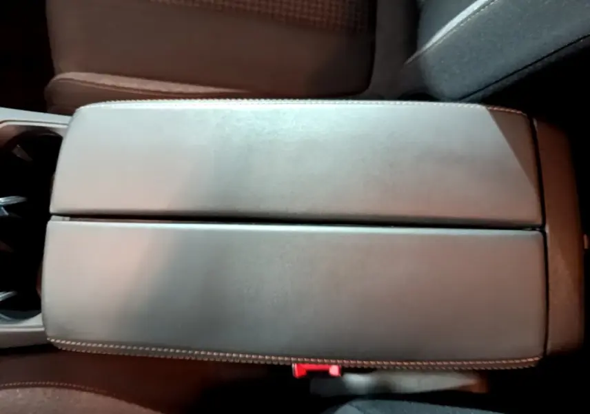 Vue plongeante sur l'accoudoir central en cuir gris clair du Peugeot 5008, avec surpiqûres blanches visibles.