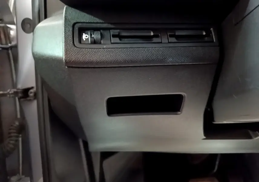 Vue rapprochée sous le tableau de bord côté gauche du Peugeot 5008 gris clair, montrant les commandes d’éclairage.