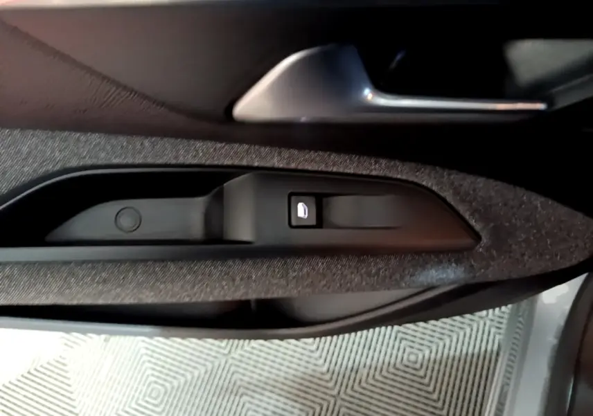Détail de la commande de verrouillage de porte sur la portière côté conducteur d’un Peugeot 5008 gris clair.