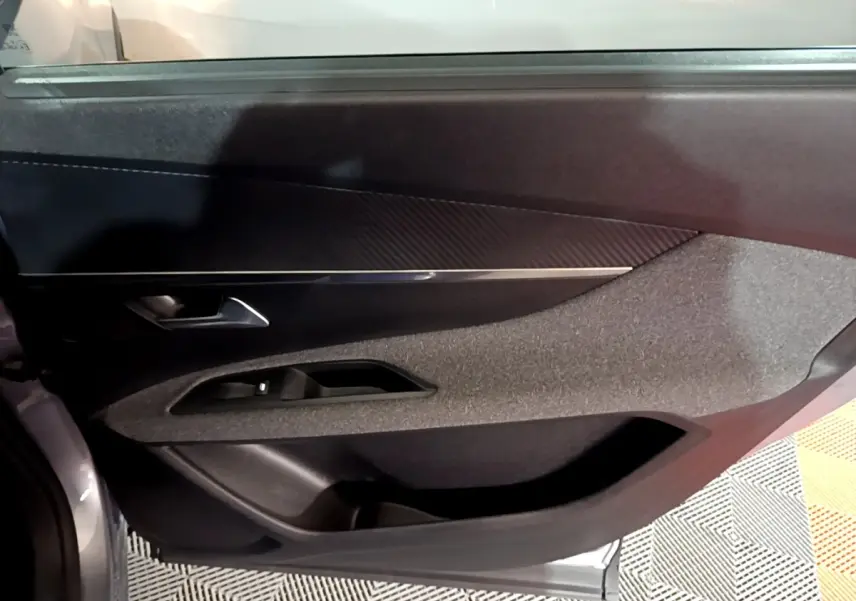 Détail de la porte intérieure côté conducteur du Peugeot 5008 gris clair, avec habillage tissu et plastique noir.