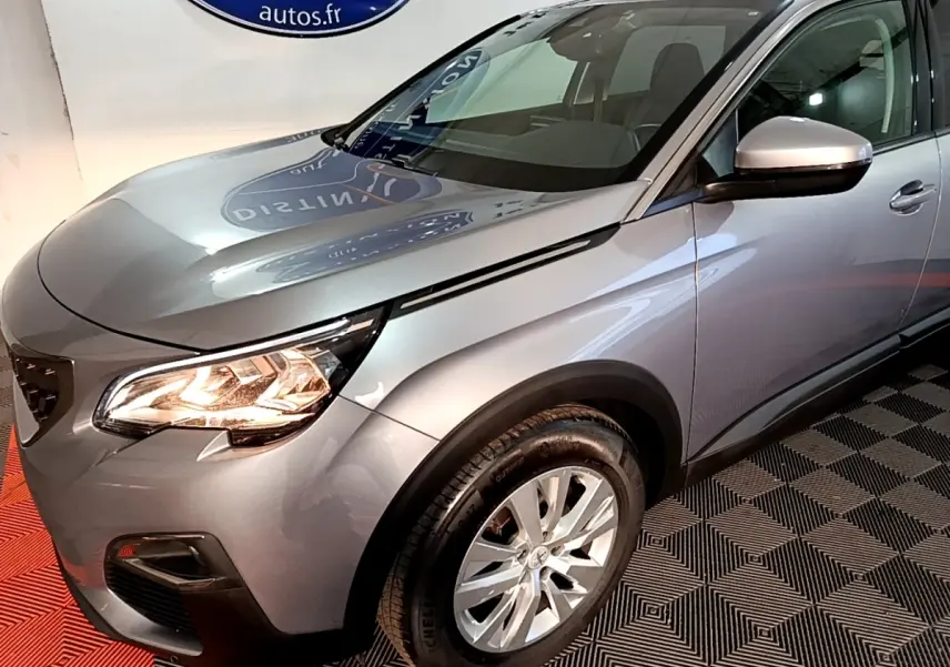 Vue 3/4 avant droit d’un Peugeot 5008 gris clair avec phares allumés et jantes alliage visibles.