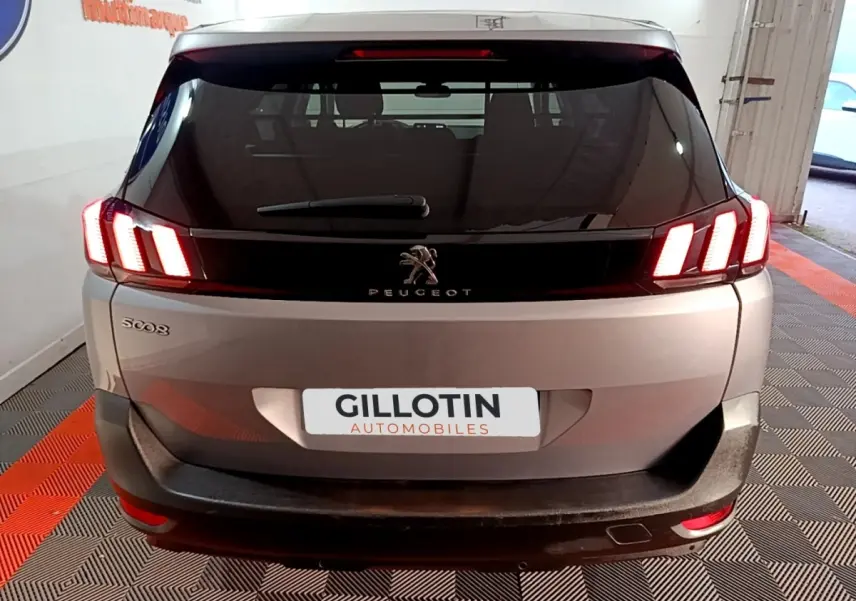 Vue arrière d’un Peugeot 5008 gris clair avec feux LED allumés et logo Peugeot bien visible sur le hayon.