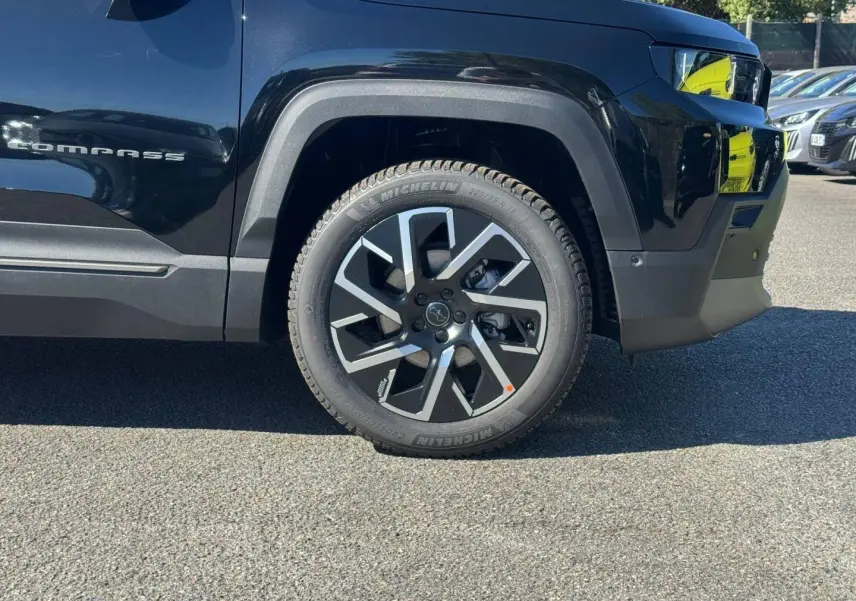 Gros plan sur la roue avant droite et la partie latérale noire du Jeep Compass Vulcano avec logo Compass visible.