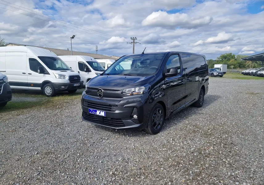 Vue 3/4 avant d'un Citroën Jumpy XL gris titane avec jantes tôles 17 pouces sur un parking extérieur.