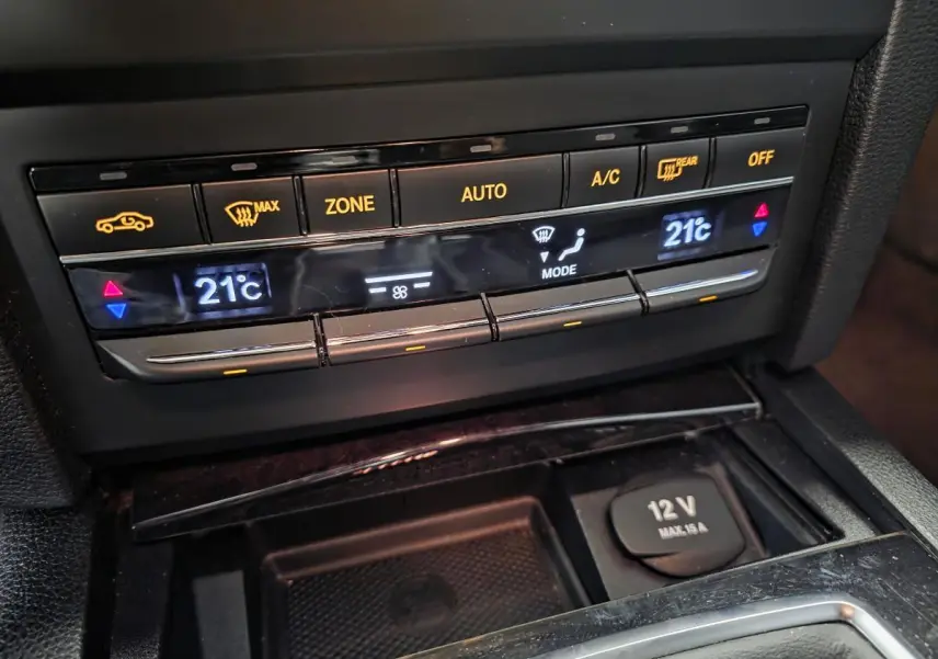 Gros plan sur la console centrale de la Mercedes Classe E Coupé 2012, affichant la climatisation automatique à 21°C.