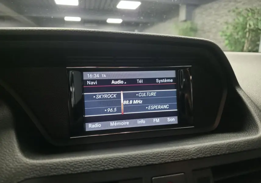 Écran central de navigation et audio allumé dans l'habitacle d'une Mercedes Classe E Coupé gris 2012.