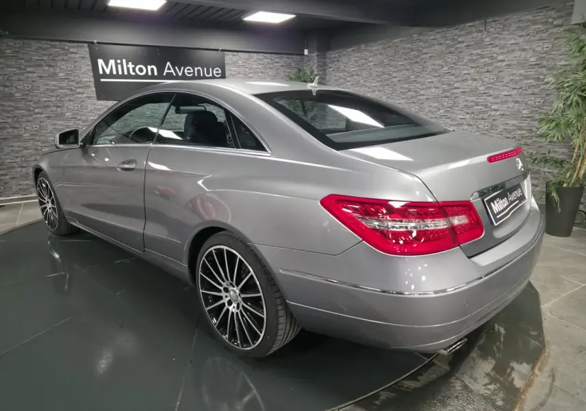 Vue 3/4 arrière droite d'un coupé Mercedes Classe E gris métallisé avec jantes alliage 19 pouces et feux arrière LED.