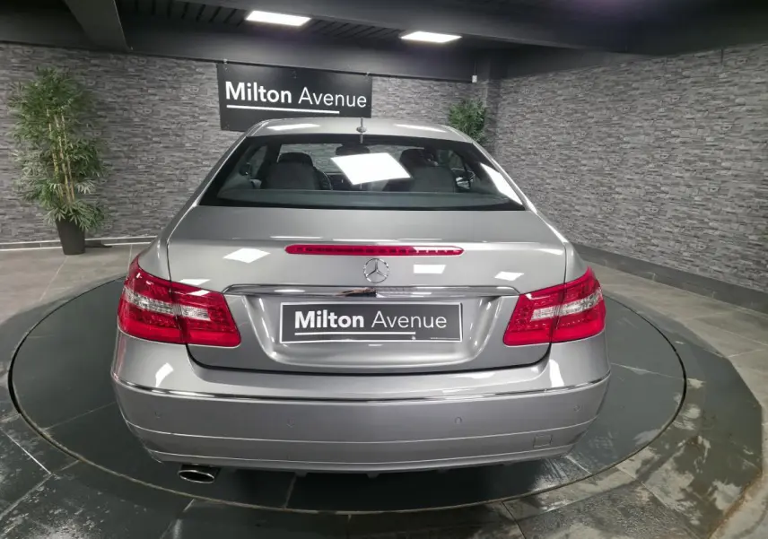 Vue arrière d'une Mercedes Classe E Coupé E 200 gris métallisé avec feux rouges et plaque Milton Avenue.