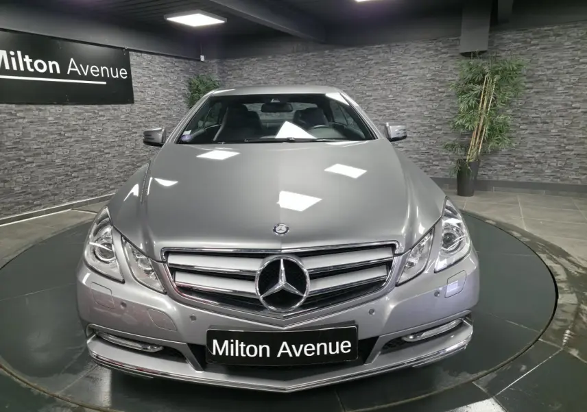 Vue avant d'une Mercedes Classe E Coupé gris métallisé avec calandre chromée et logo étoile bien visible
