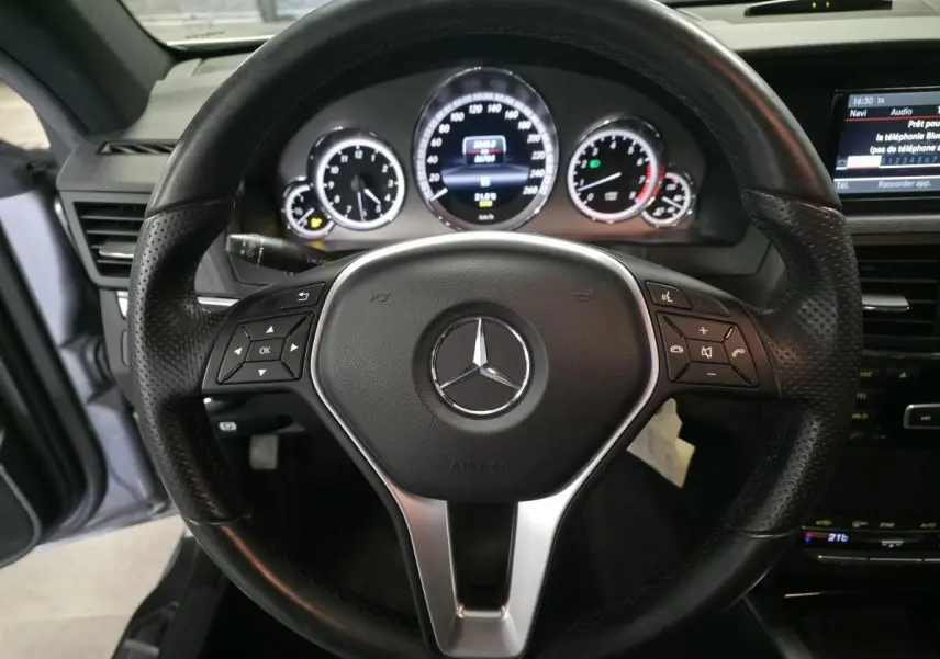 Volant en cuir noir perforé avec commandes multifonctions, tableau de bord et écran central d'une Mercedes Classe E Coupé 2012.