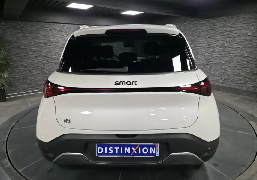 Vue arrière d'une Smart #1 électrique blanche avec feux arrière reliés par une bande lumineuse rouge.