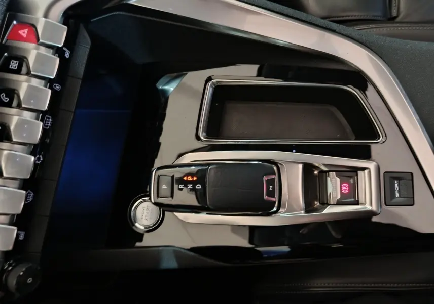 Vue rapprochée de la console centrale noire brillante du Peugeot 3008 avec levier de vitesse automatique et bouton start/stop.