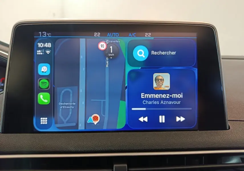 Écran tactile central du tableau de bord du Peugeot 3008 blanc, affichant navigation et musique en streaming.
