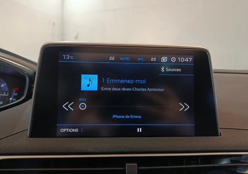 Écran tactile central du tableau de bord du Peugeot 3008 blanc, affichant une musique en lecture.