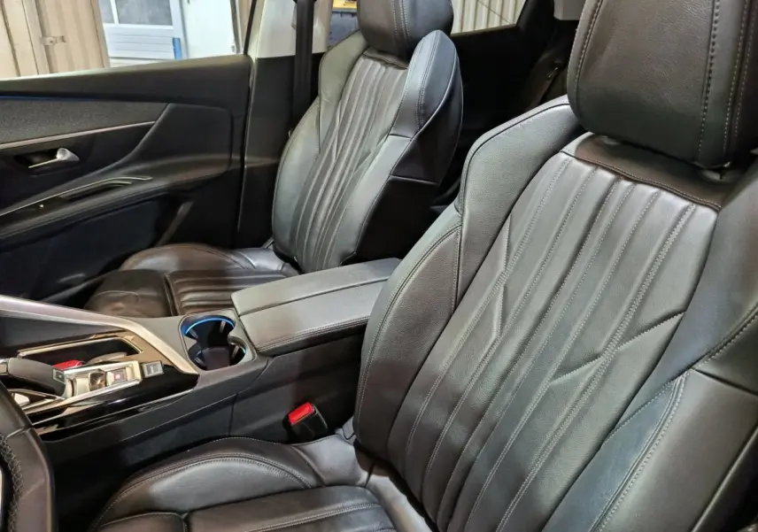 Vue intérieure côté avant droit du Peugeot 3008 2019, sièges en cuir noir et console centrale avec accoudoir.