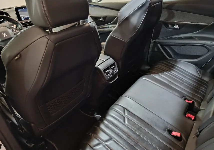 Vue intérieure arrière du Peugeot 3008 blanc, sièges en cuir noir et console centrale avec sorties d'air.