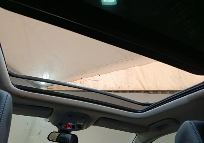 Vue intérieure du toit ouvrant panoramique du Peugeot 3008 blanc, avec ciel visible et partie des sièges avant en cuir.