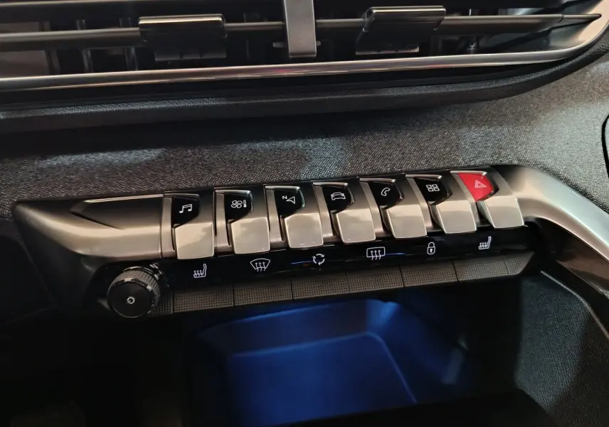 Gros plan sur la rangée de boutons argentés et noirs du tableau de bord du Peugeot 3008 blanc, version Allure 2019.