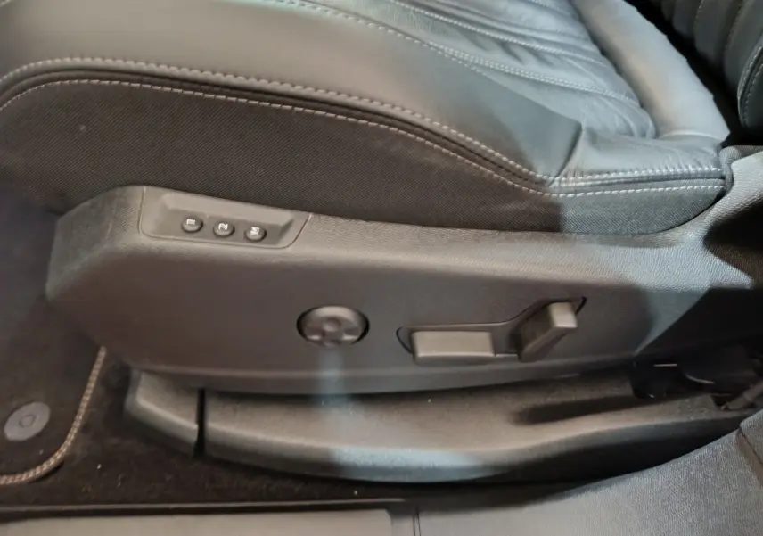 Gros plan sur les commandes de réglage électrique du siège avant droit en cuir noir du Peugeot 3008 blanc.