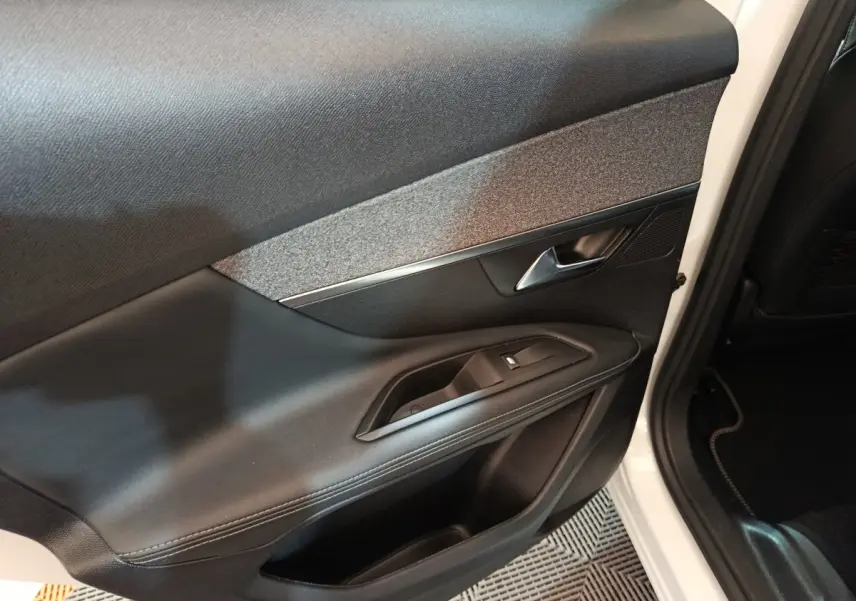 Gros plan sur la porte avant droite noire avec insert gris et poignée argentée du Peugeot 3008 blanc 2019.