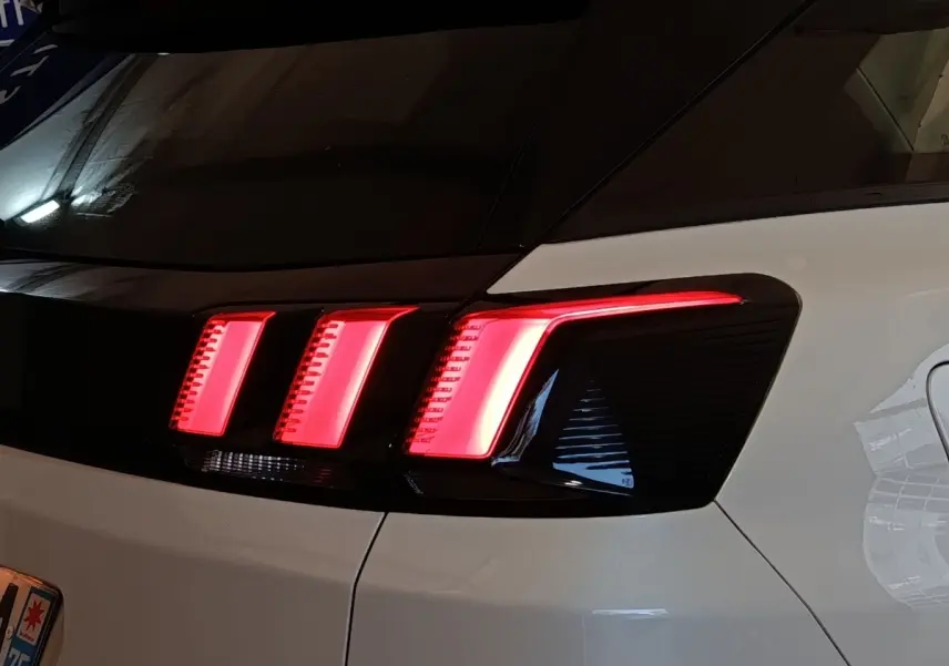 Feu arrière droit allumé d’un Peugeot 3008 blanc, vue en gros plan sur la partie arrière du véhicule.