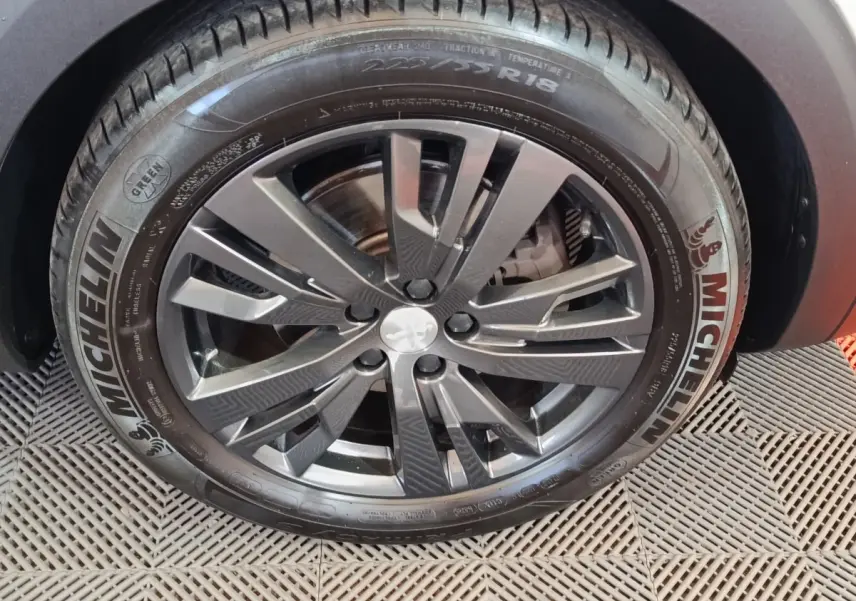 Gros plan sur la roue avant droite du Peugeot 3008 blanc, jante alliage noire avec logo lion au centre.