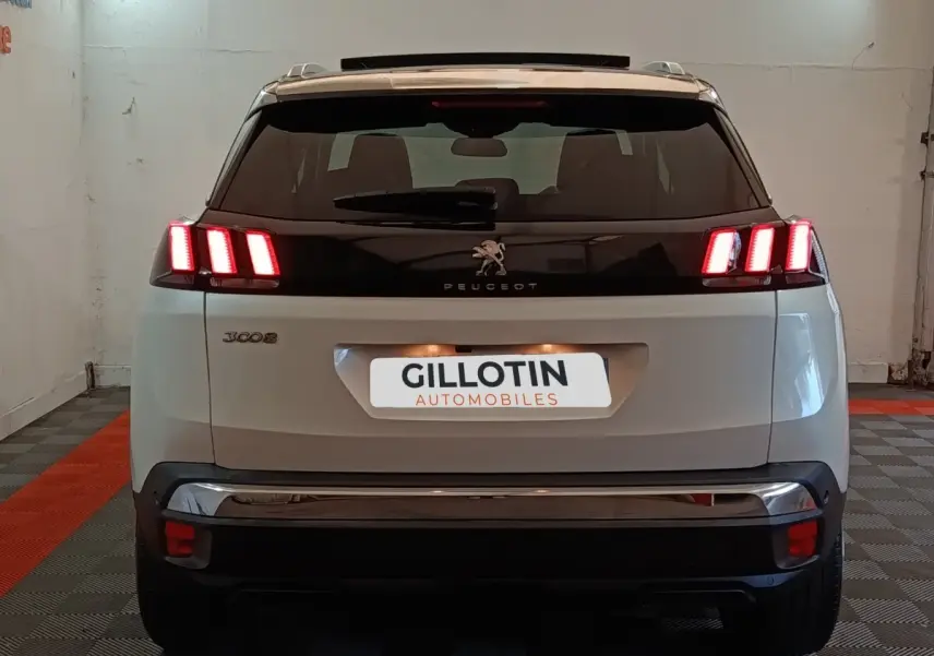 Vue arrière d'un Peugeot 3008 blanc avec feux arrière allumés et bande noire distinctive sur le hayon.