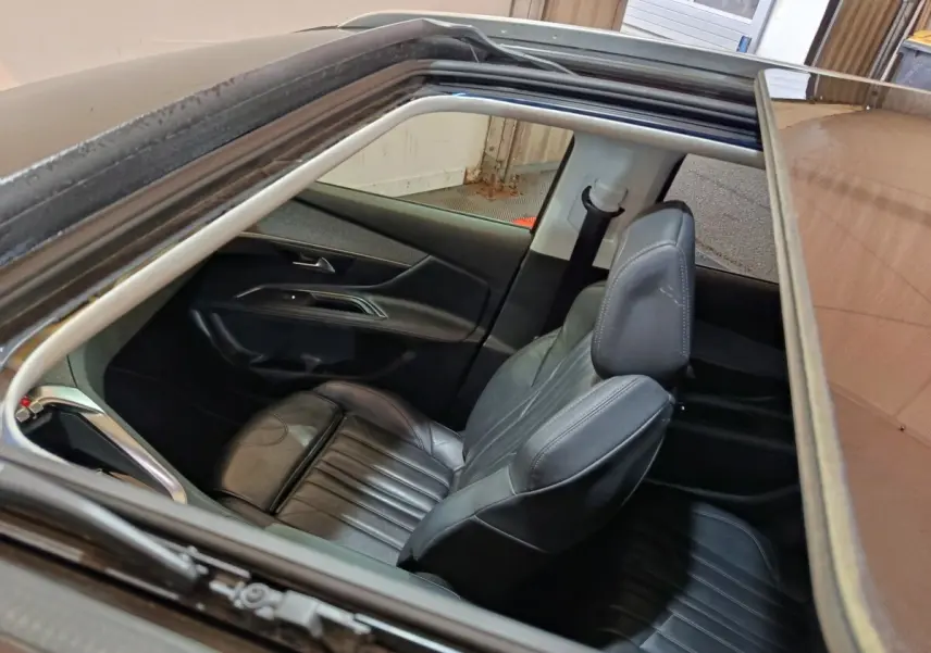 Vue intérieure par le toit ouvrant du siège avant droit en cuir noir du Peugeot 3008 blanc Puretech 2019.