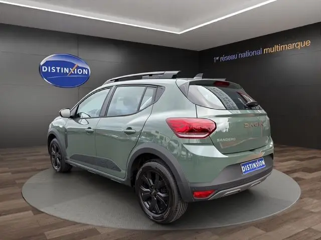 Vue 3/4 arrière gauche d'une Dacia Sandero Stepway 2025 kaki lichen avec jantes noires et toit ouvrant panoramique.