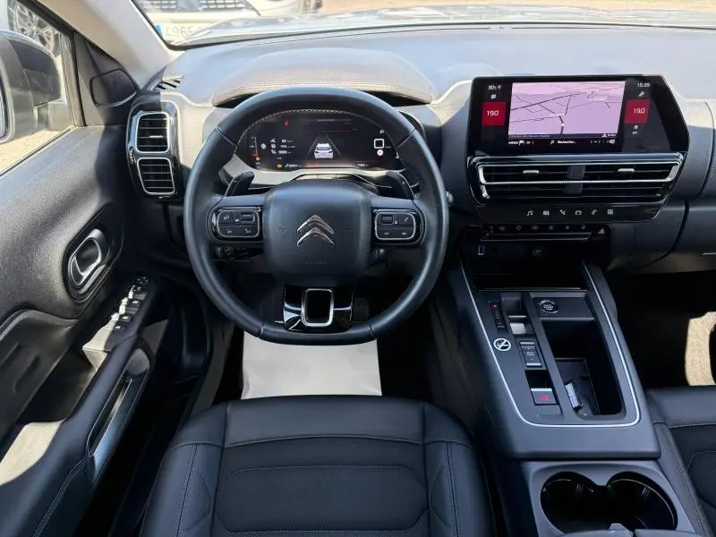 Vue intérieure frontale du tableau de bord du Citroën C5 Aircross gris acier, avec volant multifonction et écran tactile GPS.