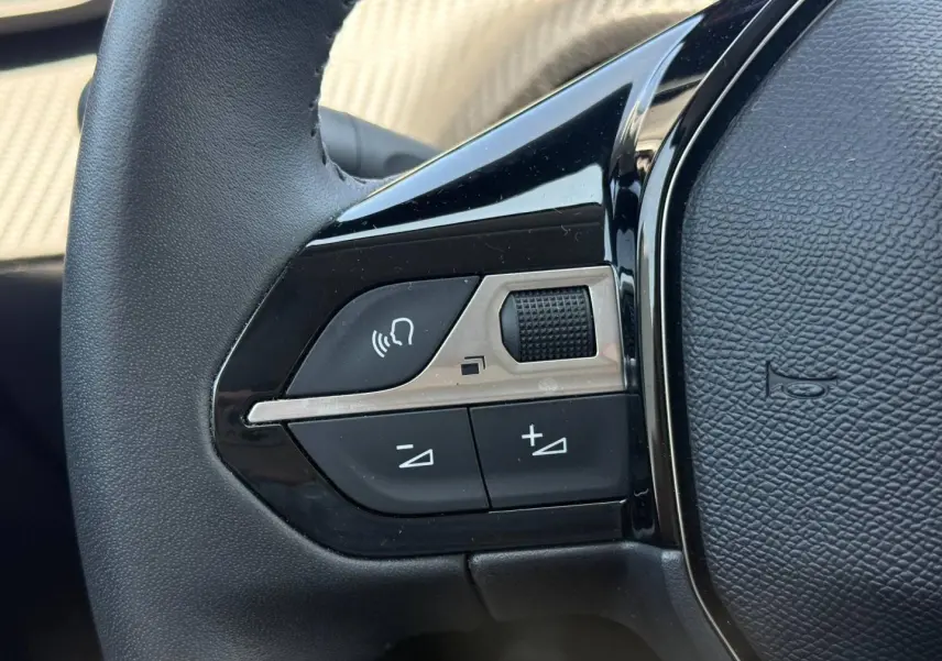 Gros plan sur les commandes audio au volant noir de la Peugeot 208 1.2 100ch Allure gris Artense.