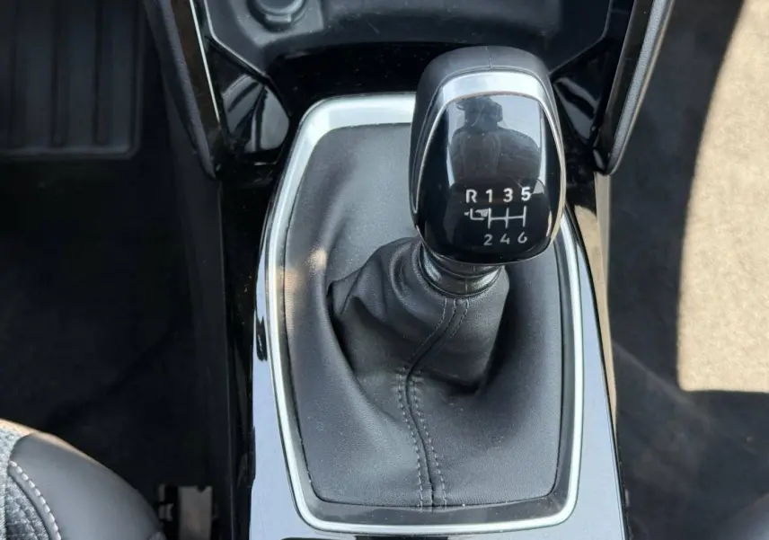 Gros plan sur le levier de vitesses manuel noir de la Peugeot 208 1.2 100ch Allure, entouré de garniture brillante.