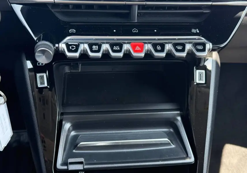 Vue rapprochée de la console centrale noire avec commandes climatisation et ports USB de la Peugeot 208 gris Artense 2025.