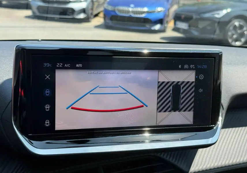 Écran tactile intérieur de la Peugeot 208 2025 montrant la caméra de recul avec vue 360° et tableau de bord noir.