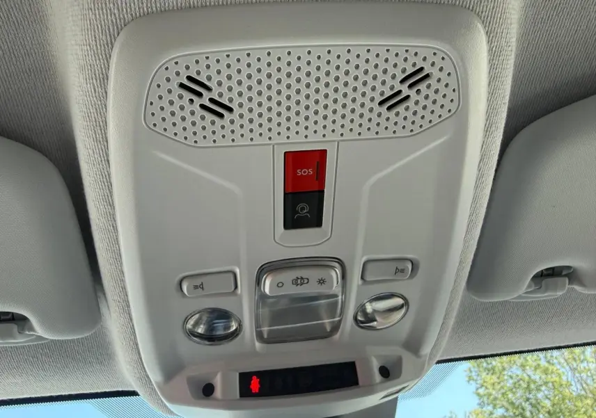 Vue en contre-plongée du plafonnier gris clair avec bouton SOS rouge dans l’habitacle d’une Peugeot 208 2025.