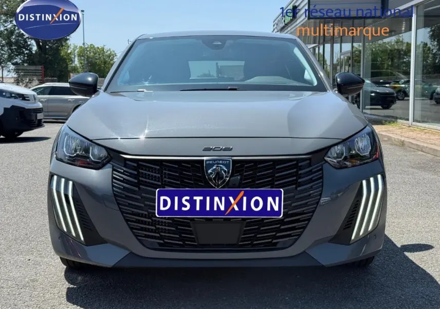Vue frontale d'une Peugeot 208 gris Artense avec phares LED et calandre noire distinctive.