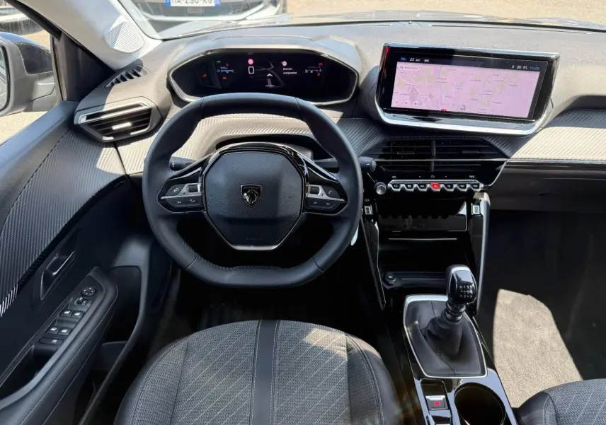 Vue intérieure avant de la Peugeot 208 1.2 100ch Allure, volant compact, écran tactile et levier de vitesse manuel.