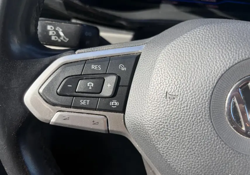 Gros plan sur le volant cuir du Volkswagen Transporter blanc, avec commandes de régulateur de vitesse visibles.
