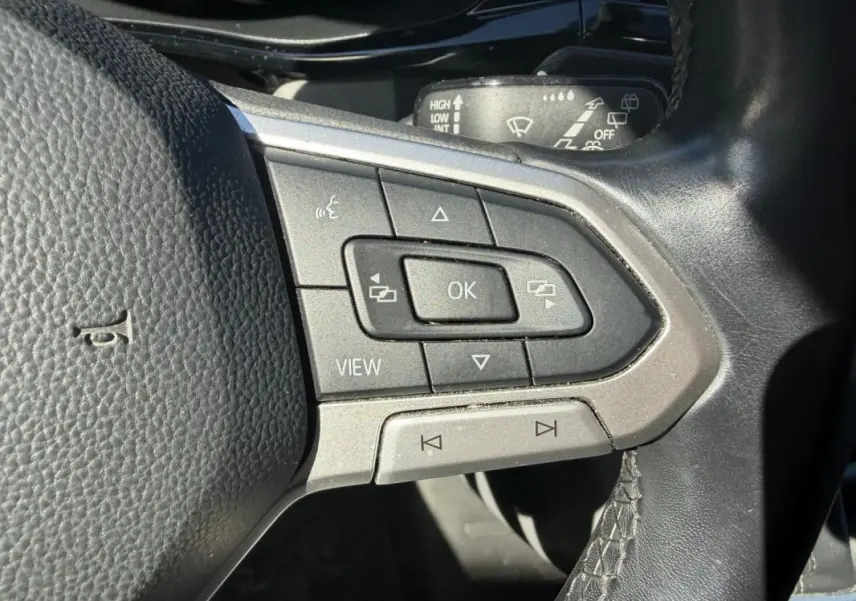 Gros plan sur les commandes multifonctions du volant cuir du Volkswagen Transporter blanc, version 2020.
