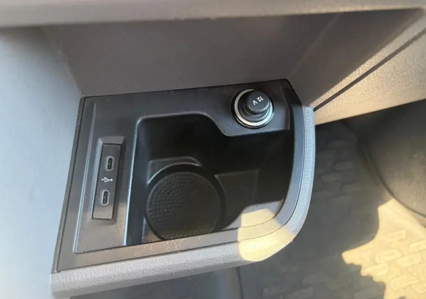 Gros plan sur la prise 12V et les deux ports USB-C dans le rangement central du Volkswagen Transporter blanc.