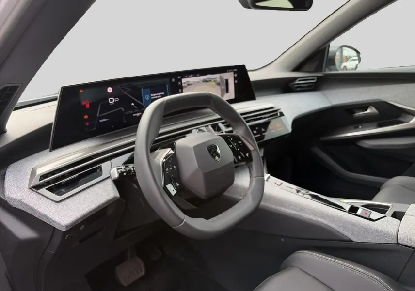 Vue intérieure côté conducteur du Peugeot 5008 Hybrid 145 allure e-dcs6 2025, tableau de bord gris clair et volant cuir noir.