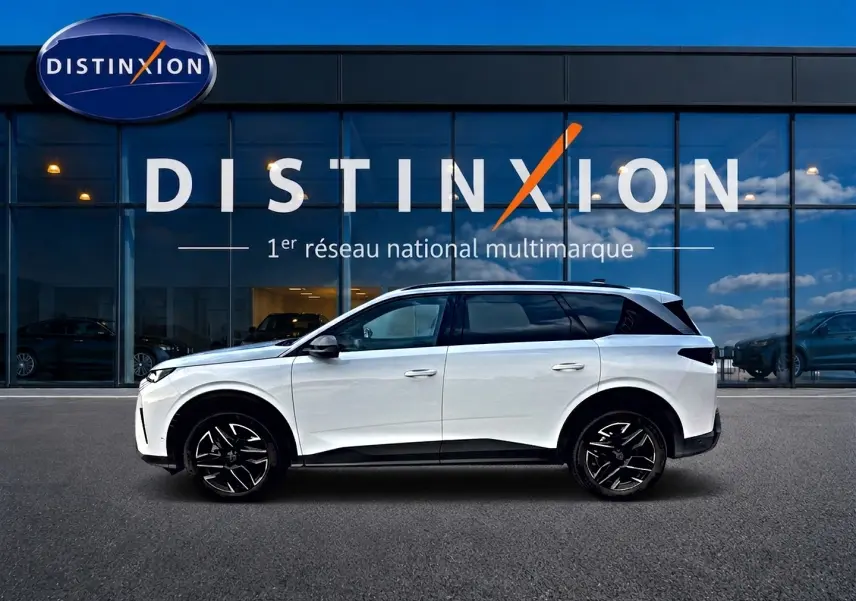 Vue de profil côté gauche d'un Peugeot 5008 blanc garé devant une vitrine avec logo Distinxion.