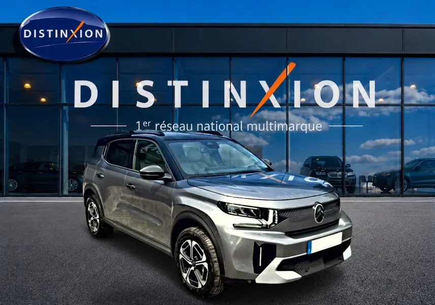 Citroën C3 Aircross gris mercury vue 3/4 avant droit devant un bâtiment vitré avec logo Distinxion.