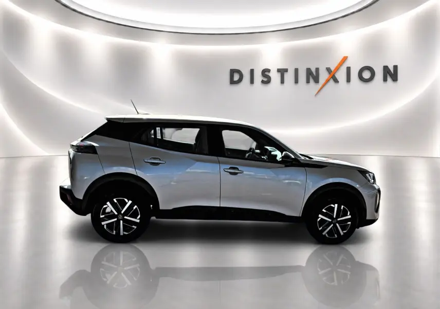 Peugeot 2008 gris en profil droit dans un showroom lumineux avec logo Distinxion en arrière-plan.