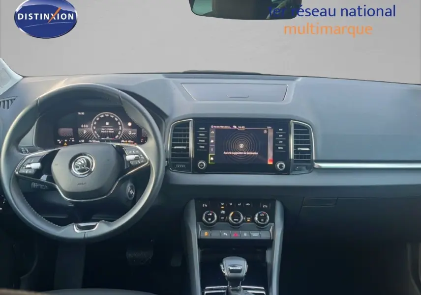 Intérieur moderne du Skoda Karoq 2023, vue frontale du tableau de bord avec écran tactile et volant multifonction noir.
