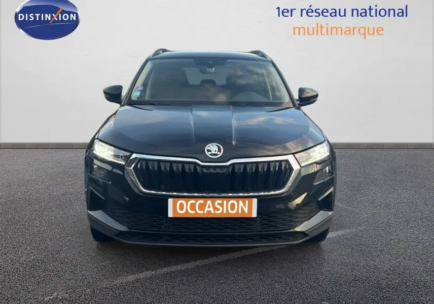 Vue frontale d'un Skoda Karoq noir Magic Metal avec calandre chromée et phares LED allumés sur fond neutre.