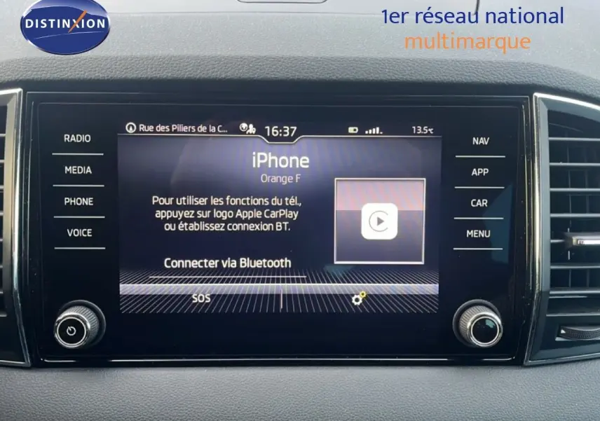 Écran central tactile du tableau de bord d'une Skoda Karoq 2023 avec interface Apple CarPlay et commandes latérales.